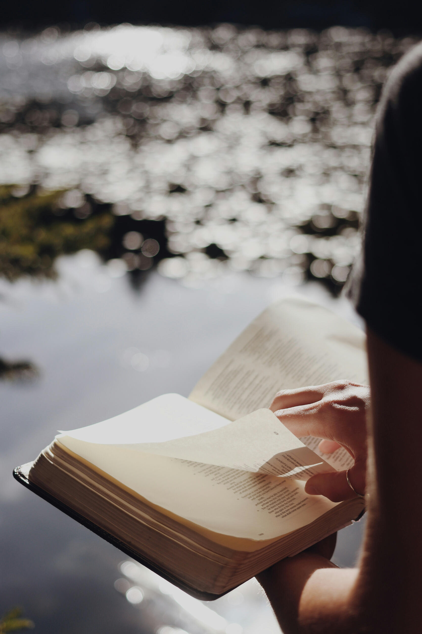 Quiet moments of reflection — many expats in Korea seek spiritual connection and community through their faith. A person flipping through a Bible beside a river, symbolizing faith and reflection for expats in Korea