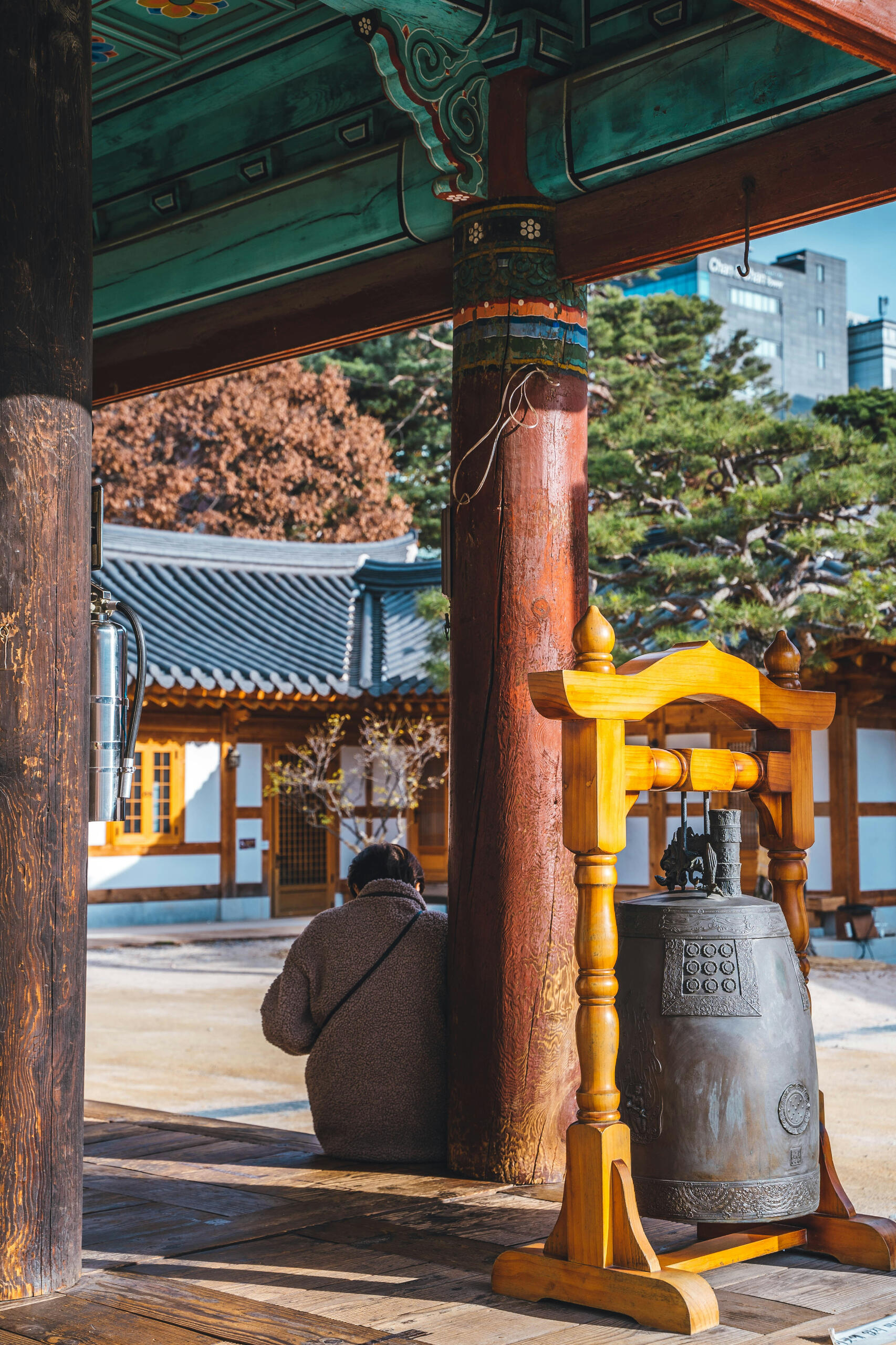 Stillness and reflection — expats in Korea often visit Buddhist temples to reconnect with inner peace, mindfulness, and cultural A person meditating at a traditional Korean Buddhist temple, surrounded by wooden architecture and a large temple bell.